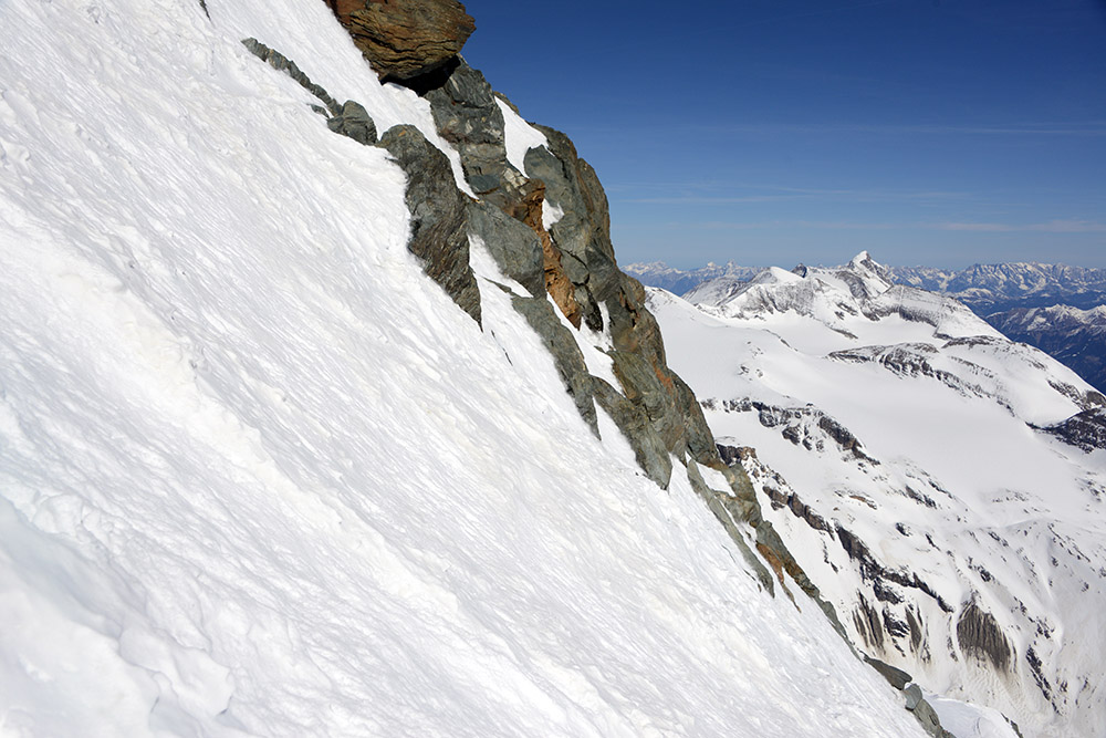 Climber ascending steep deep snow below the summit ridge of Grossglockner