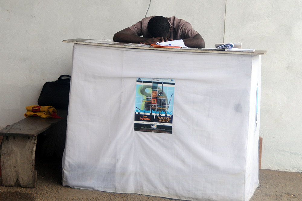 Security guard resting near an outdoor art display in Cotonou, Benin