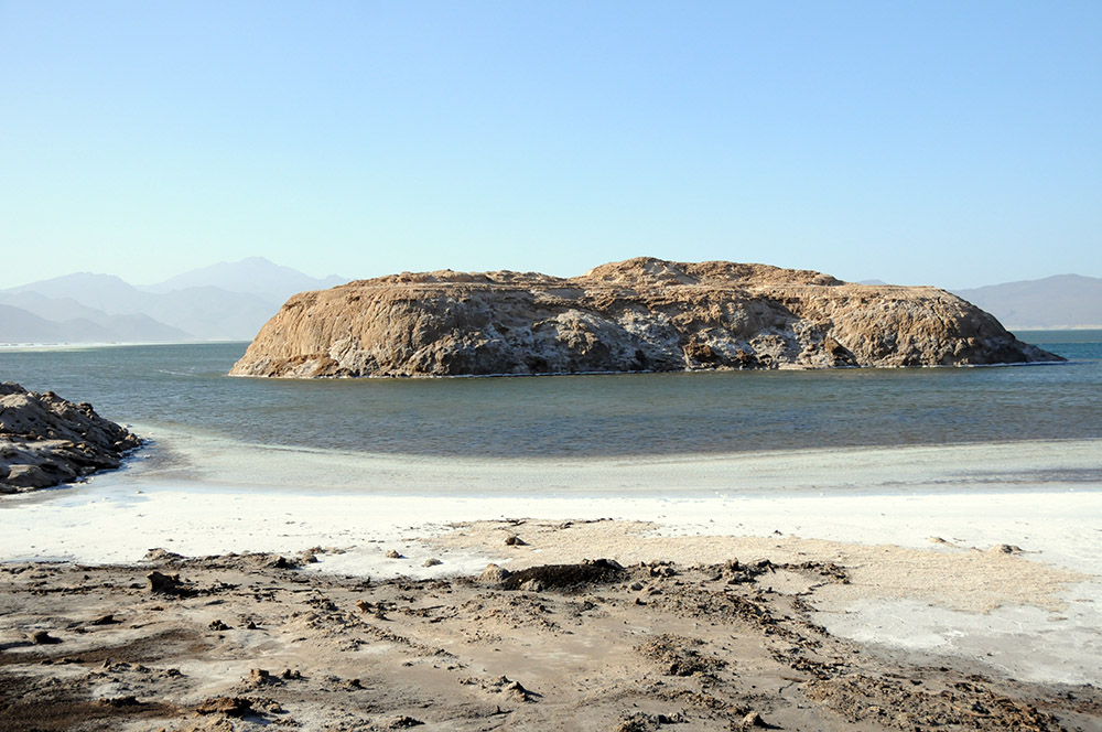 Small rocky island surrounded by the waters of Lake Assal
