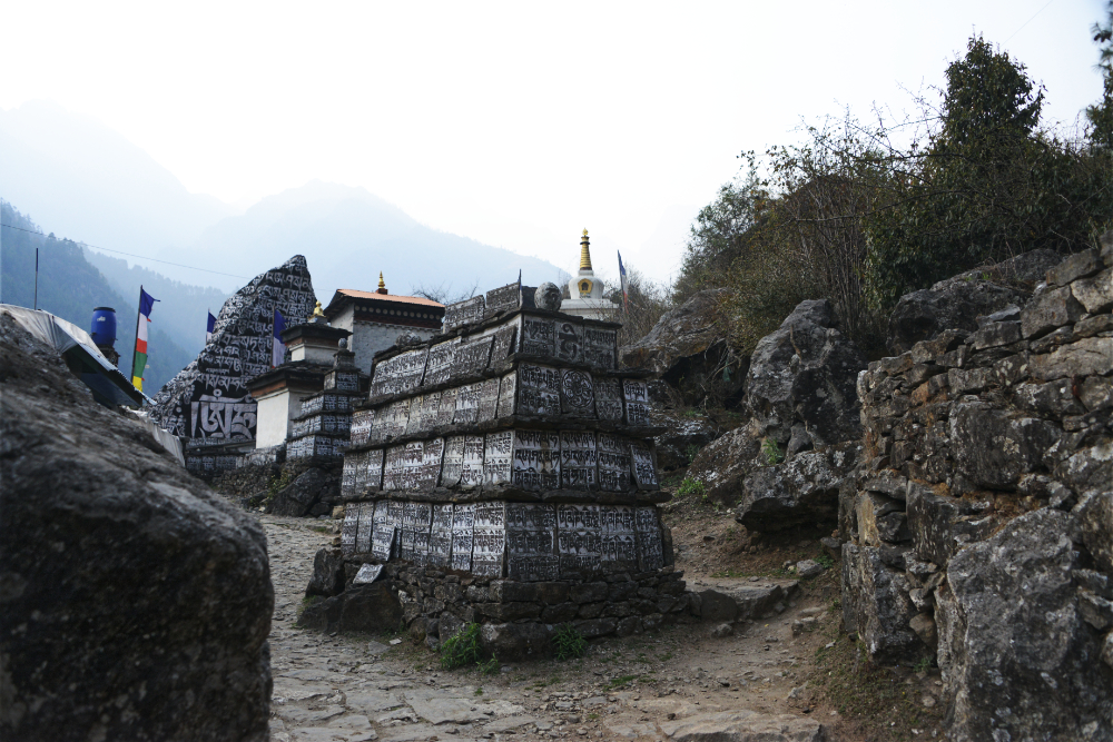 Large Buddhist mani stones with carved inscriptions along the trail near Lukla
